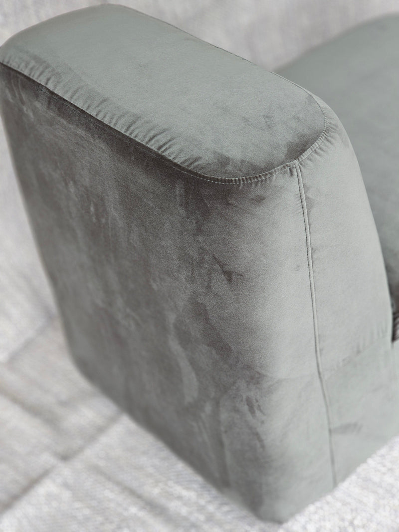 Close-up of the Omega Upholstered Armchair's plush armrest in soft grey velvet, showcasing its smooth texture and modern design.
