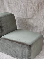 Omega Upholstered Armchair in grey velvet with wide cushioned seat and low backrest, ideal for minimalist living spaces.